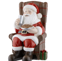 Load image into Gallery viewer, Santa Claus figurine sitting in a chair holding a mug and bowl, with a gift at his feet on a white background.