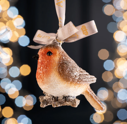 Decorative robin ornament with a ribbon against a blurred lights background