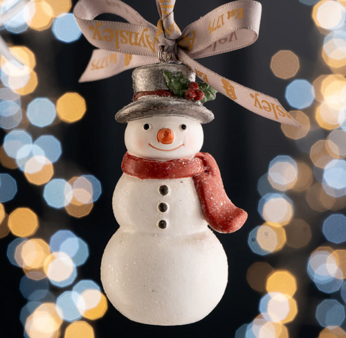 Decorative snowman ornament with a bow against a blurred lights background