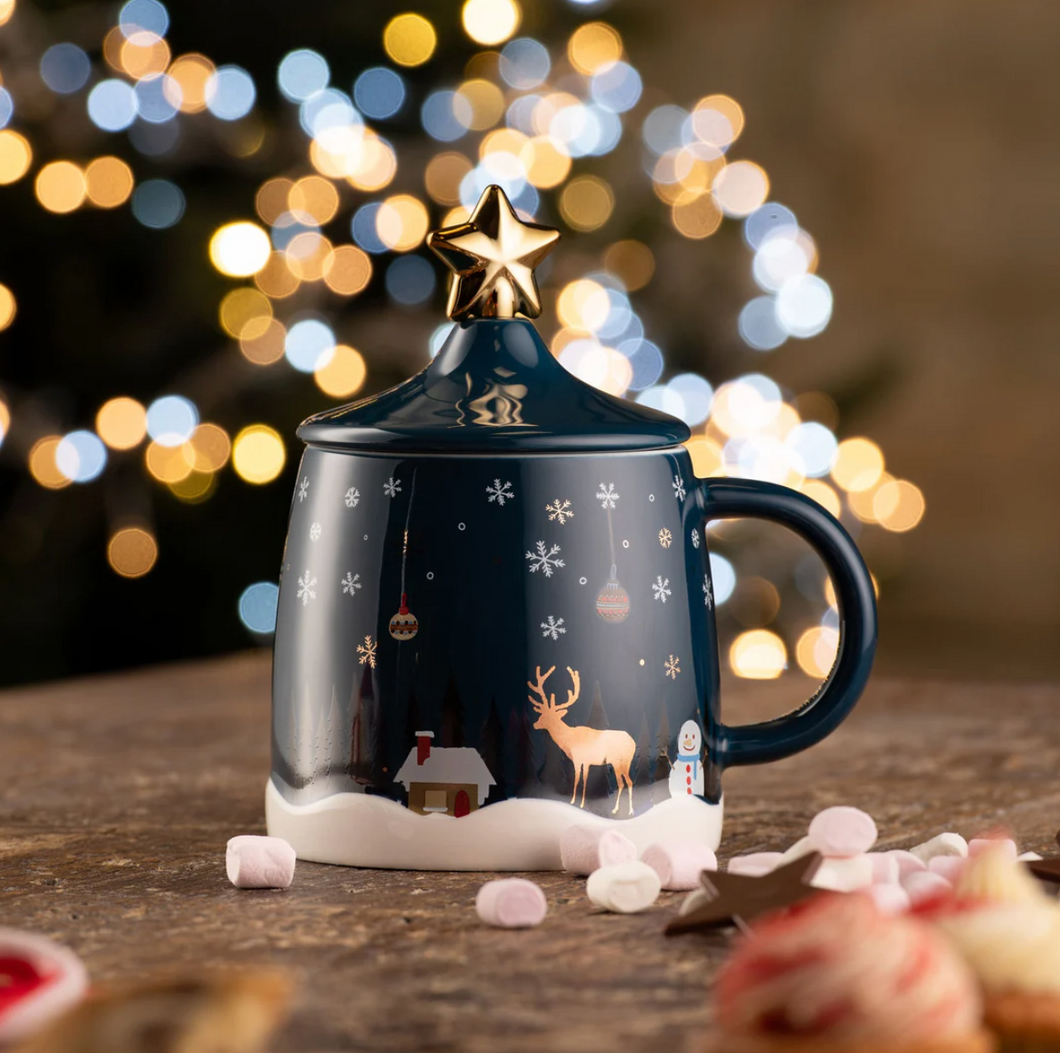 Decorative mug with reindeer design on a wooden surface with blurred lights in the background