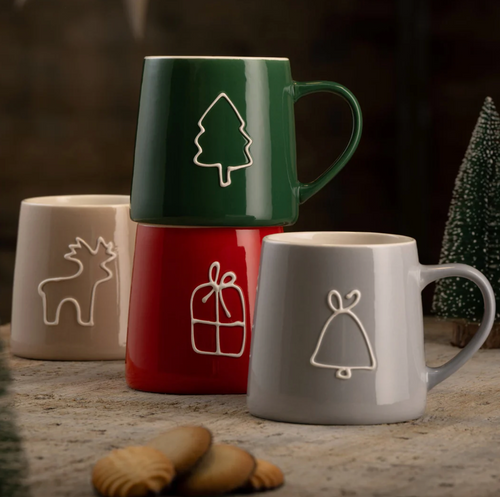 Four mugs with Christmas-themed designs on a wooden surface.