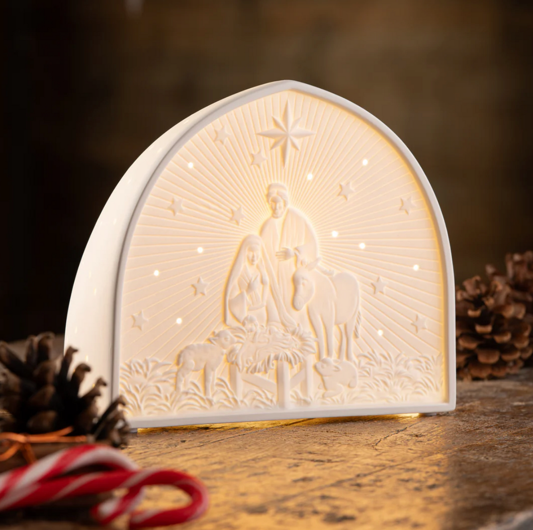 Decorative night light with nativity scene design on a wooden surface.